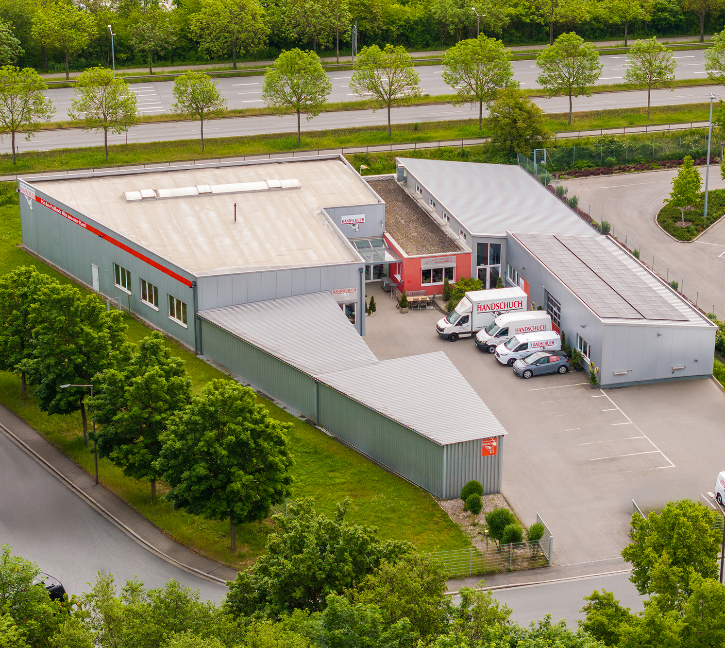 Luftbild des Firmengeländes von Handschuch mit Lagerhalle und Servicefahrzeugen
