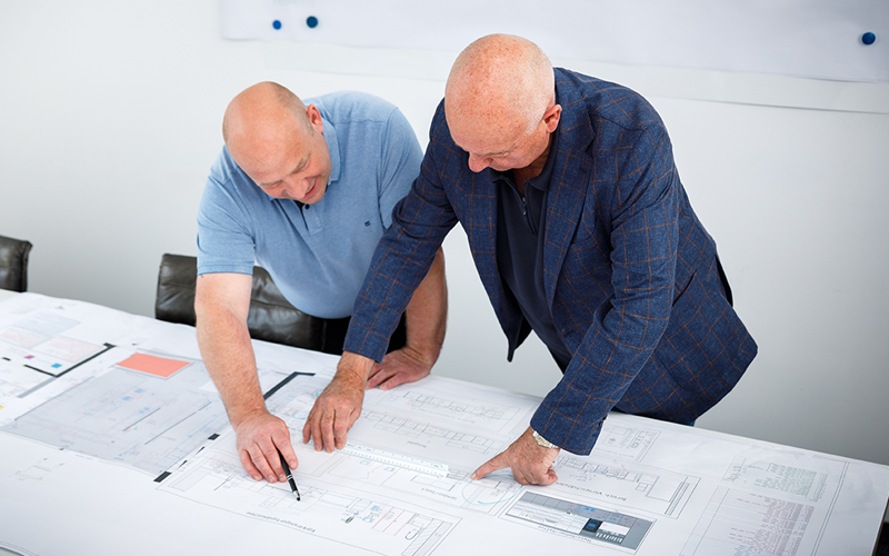 Zwei Mitarbeiter besprechen Baupläne für eine Küchenplanung